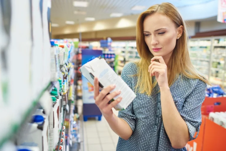Una mujer mira atentamente la etiqueta de un producto en un supermercado