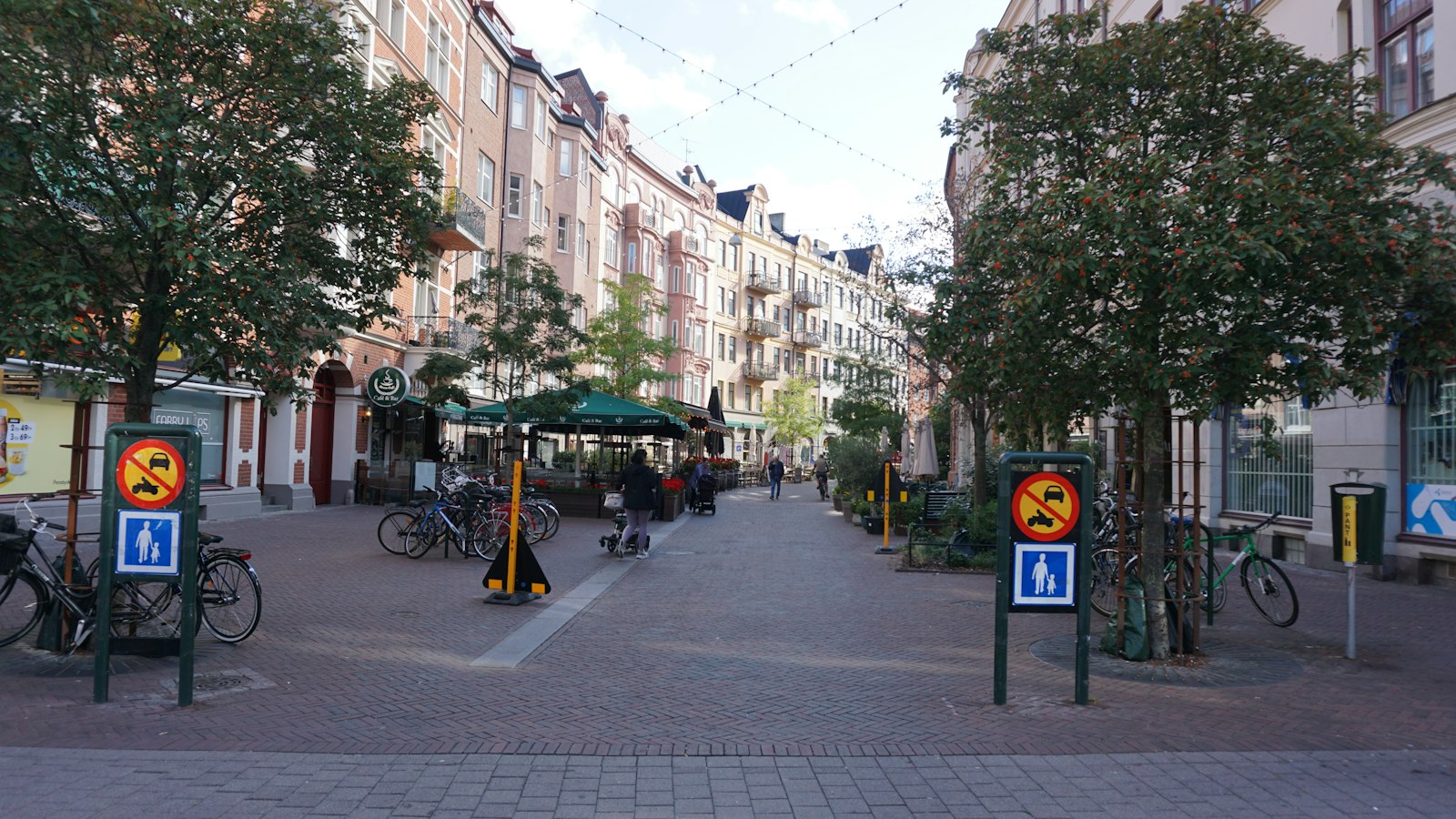 Calle peatonal con pavimento de ladrillo, árboles y edificios