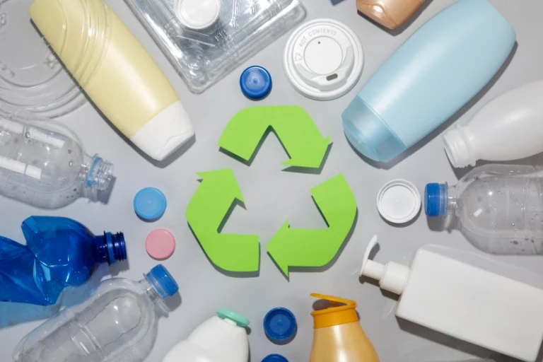 SImbólo de reciclaje rodeado de residuos de plástico (botellas, tapones, dosificadores, botes...)