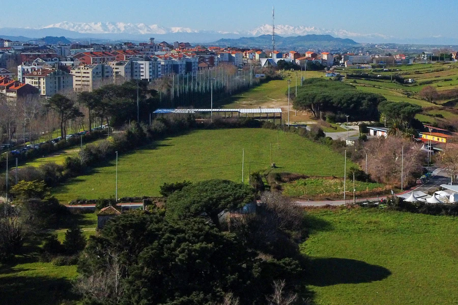 Vista aérea de la periferia de una ciudad, con prados, equipamientos y nuevos desarrollos urbanos